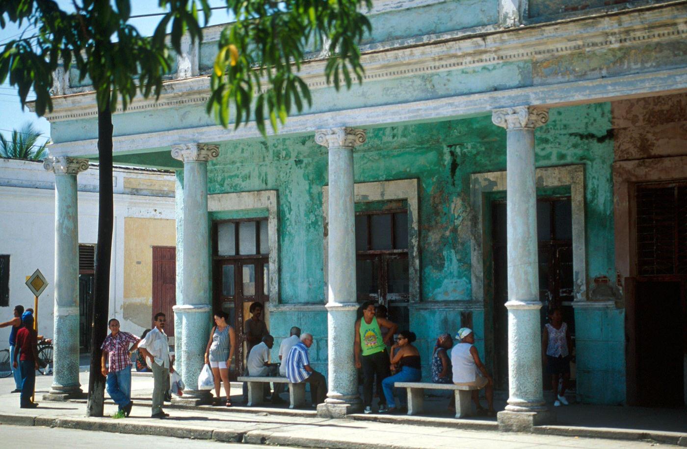 Cuban men and women standing under the arcade of a building in Cienfuegos, Cuba, 1990s.