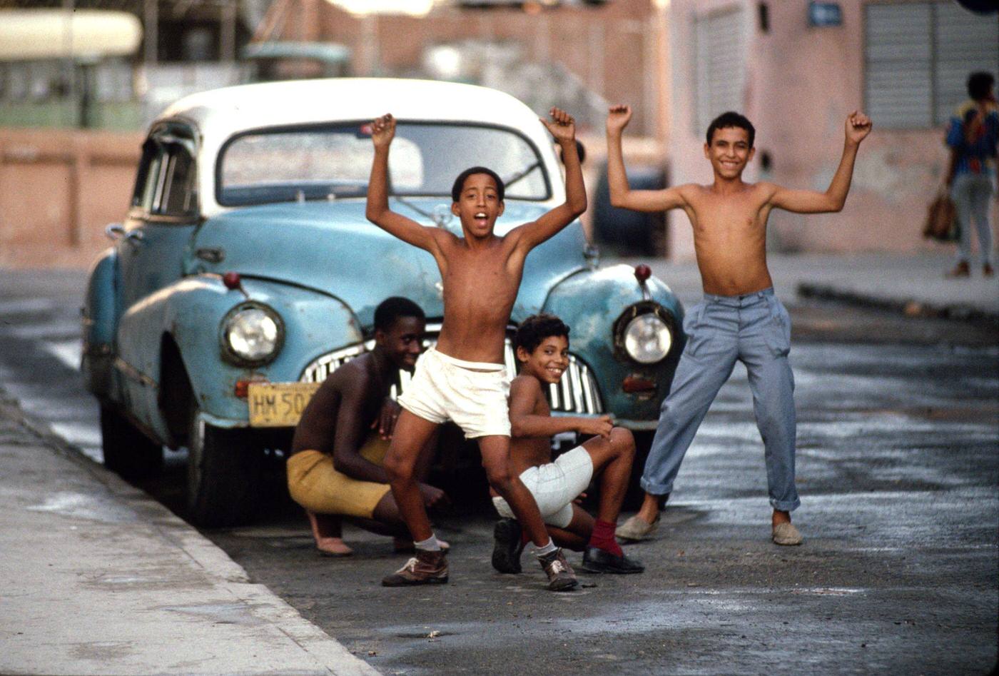 Young Cuban boys having fun as they clean a 1950's American car in downtown Havana, Cuba, 1991.