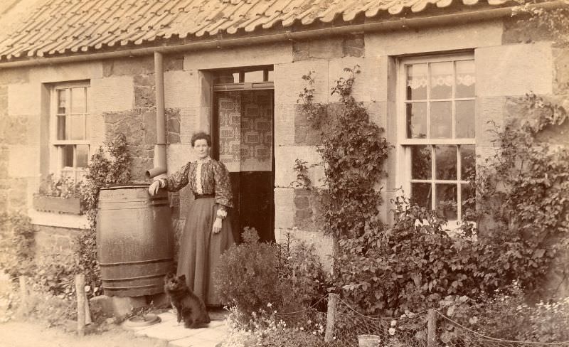 Edwardian lady and dog standing outside a single storey house