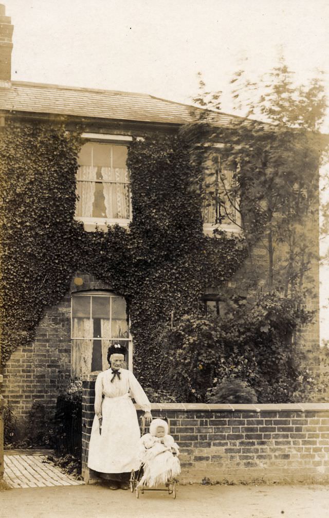 Lady in a bonnet outside terrace house with a toddler in a pram