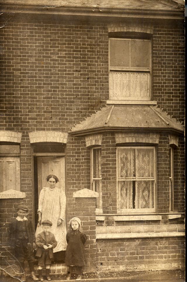 Woman and three children outside a small terrace house