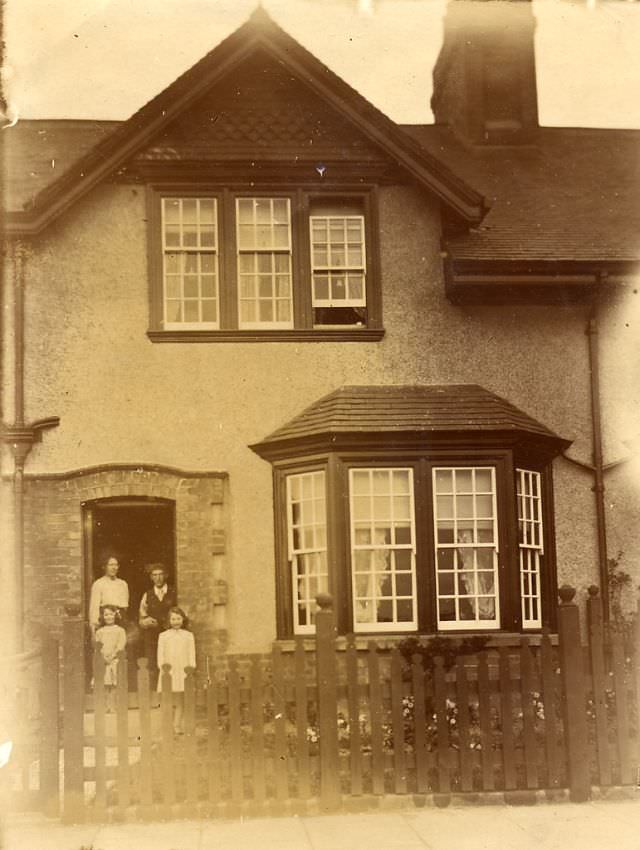 A family stand on the doorstep of their pebbledashed house