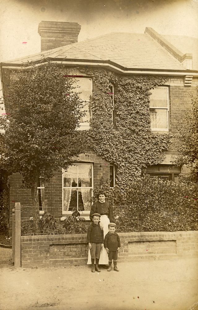 A small Edwardian family outside their ivy-clad house