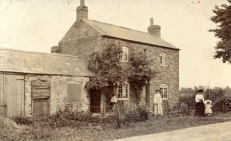 A small rural house with some of the inhabitants standing outside