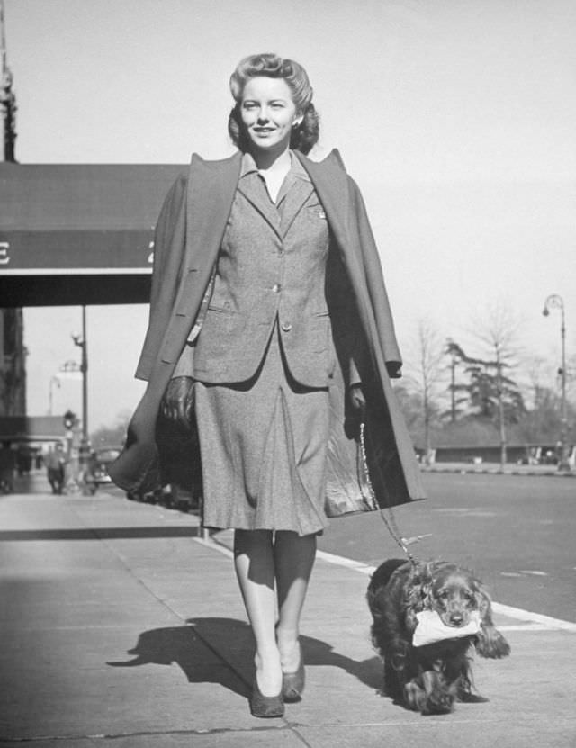 Model Mimi Berry walked her cocker spaniel, who carried a package for her, 1944.