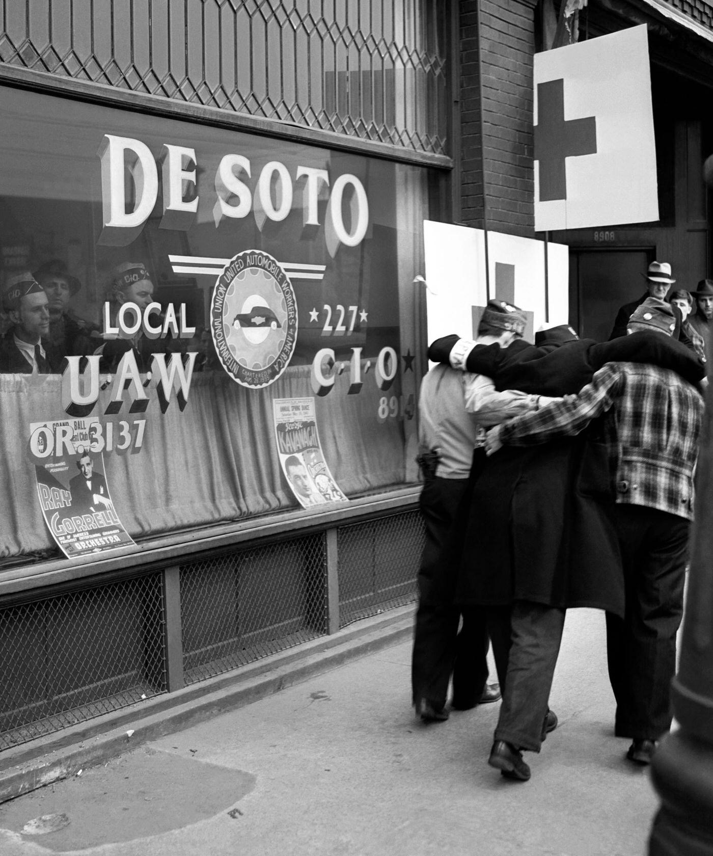 Two men carry a victim into the De Soto local United Auto Workers (UAW) headquarters after being injured during the riots over the labor dispute at the Ford River Rouge complex in Dearborn, Michigan, April 1941.