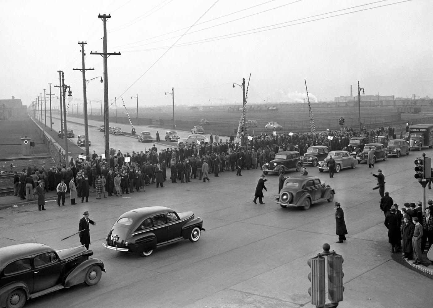A large crowd of people stand on the sidewalk during the Detroit Ford Motor Company Labor Strike near the Ford River Rouge complex in Dearborn, Michigan, April 1941