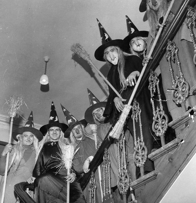 A group of men dressing as witches while holding brooms in their hands, 1922.