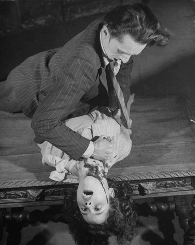 Actor dramatizing the realistic stabbing trick in production at the Grand Guignol Theater.