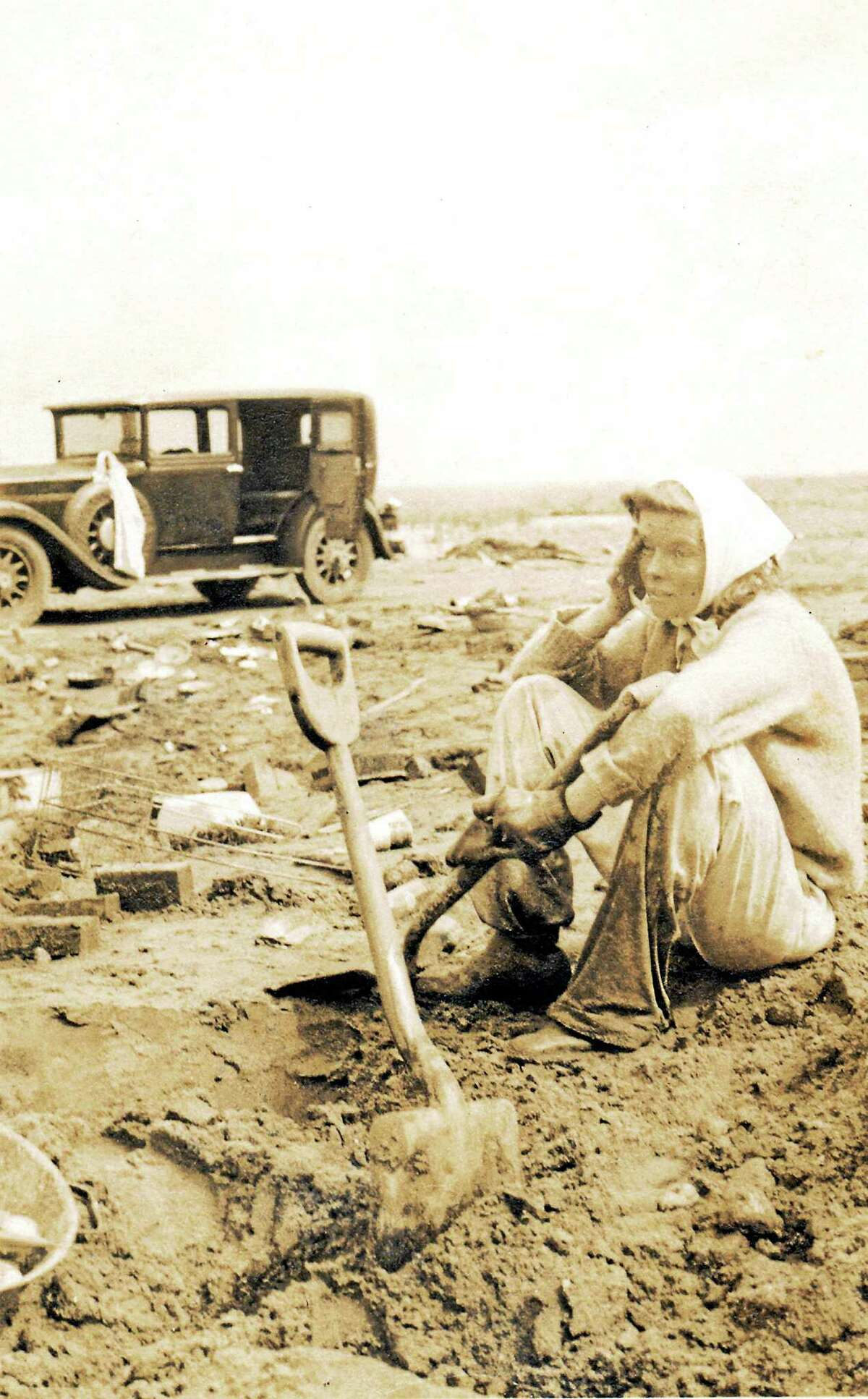 Hollywood actress, Katharine Hepburn, sitting in the muddy debris of her destroyed family beach home after the Great New England Hurricane of 1938.