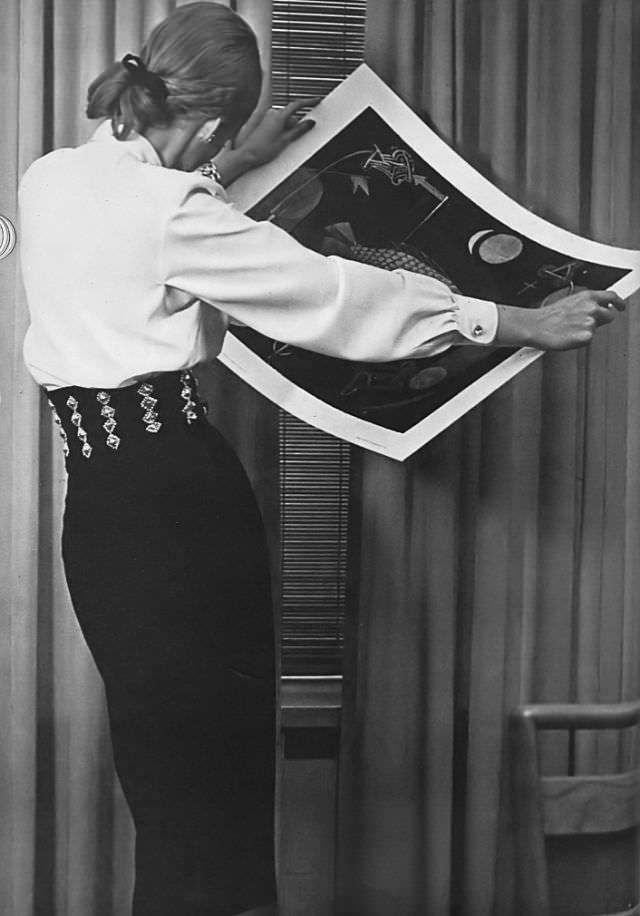Model in white jewel-buttoned blouse by Florence Gainor and wide decorated belt by Midtown, Vogue, 1945.