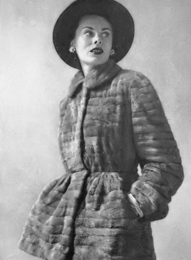 Meg Mundy in ermine tunic, its waist is tight and peplum wide, by Maximilian, midnight-blue beaver hat by Lilly Daché, Harper's Bazaar, 1947.