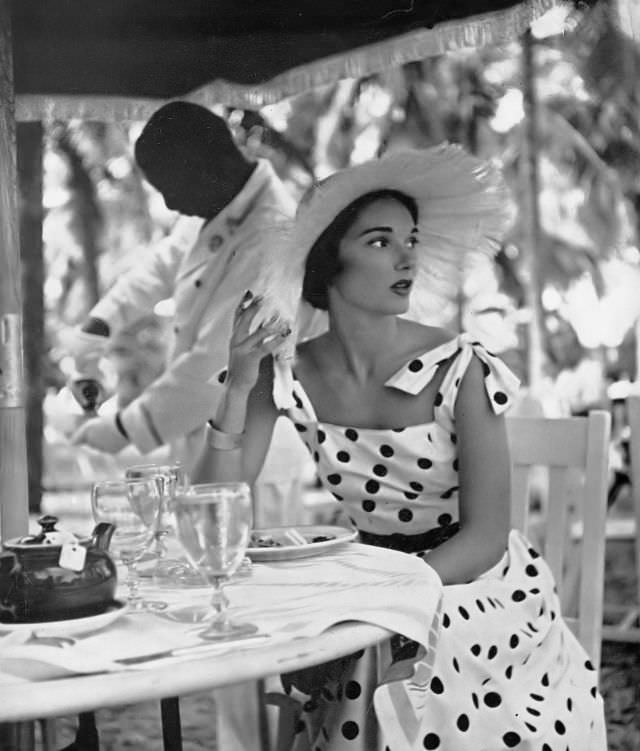 Marilyn Ambrose in sun-dress of white cotton poplin with navy blue coin dots by L'Aiglon, at the British Colonial Hotel at Nassau, Harper's Bazaar, 1948.