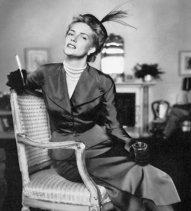 Model in plum colored faille two-piece with winged lapels and skirt with loose wrap-around panel by Paul Parnes, Harper's Bazaar, 1949.