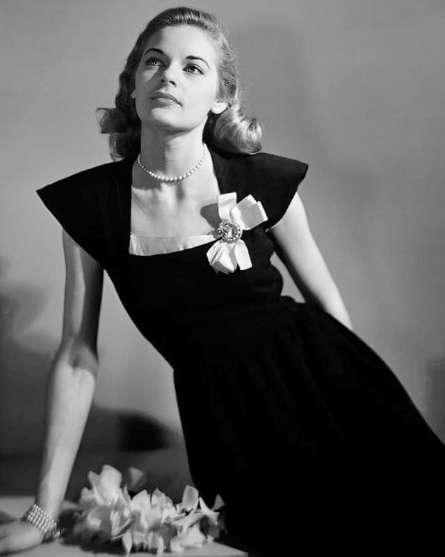 Model in black dress with pink bordered neckline, bow in corner, Marvella bracelet, Glamour, 1945.