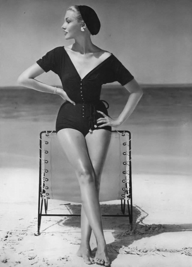 Liz Pringle in sleeved bathing dress of clinging black jersey with gilt hooks and eyes and gilt-balled belt by Claire McCardell, May 1, 1953