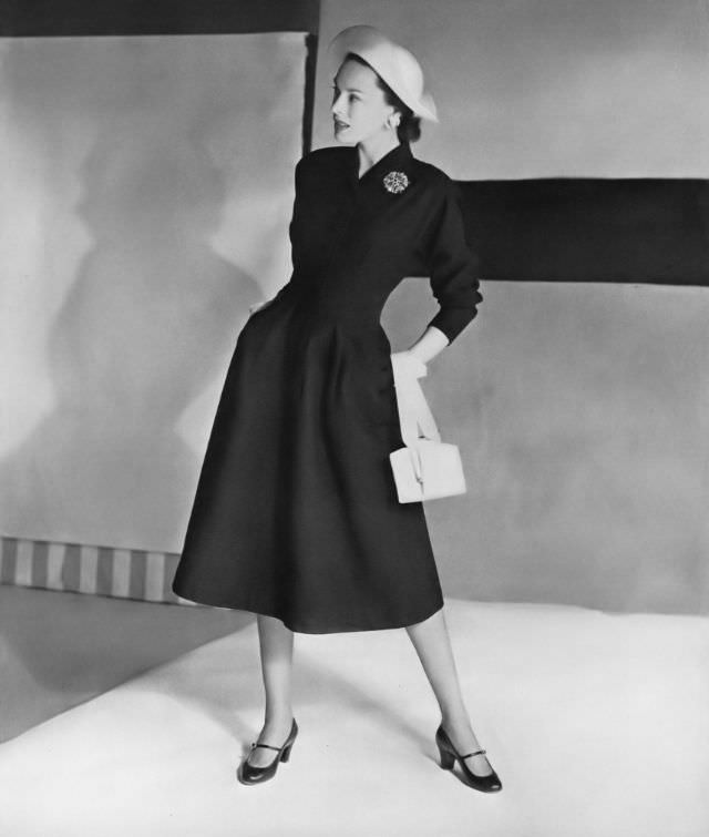 Meg Mundy in a city-black waffle-piqué coat-dress by Mildred Orrick, straw harlequin-shaped hat, white calf bag by Bienen-Davis, all at Bergdorf Goodman, Vogue, April 15, 1947