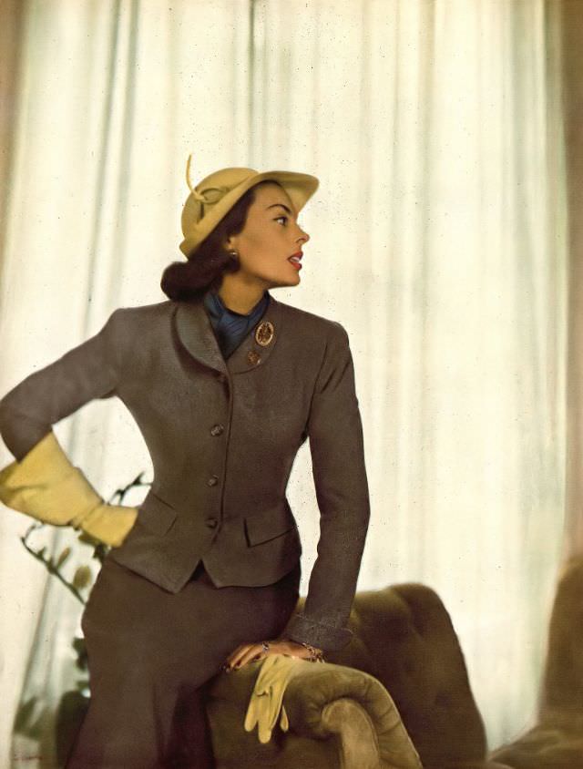 Meg Mundy in two-toned Hockanum flannel suit, the darker skirt is flared, by Roxspun, citron yellow gloves and hat by Lilly Daché, lapel coins by Shapiro, Harper's Bazaar, September 1947