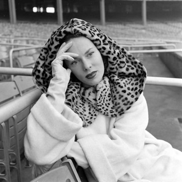 Meg Mundy wearing white wool coat with leopard fur hood, Harper's Bazaar, October 1947