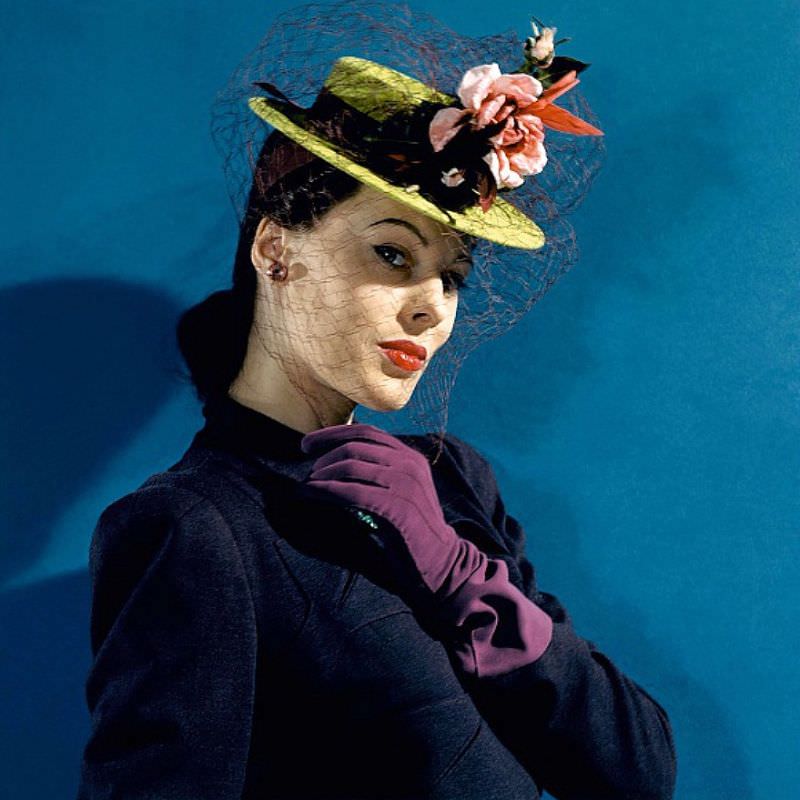 Meg Mundy in chartreuse felt hat with roses and hummingbirds, purple gloves, and purple veil and ribbons, Vogue 1941