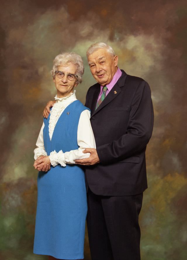Portrait of Mr and Mrs Albert Miller. Mrs Smith is on the left and is wearing a blue dress over a high-necked white top. Mr Smith is on the right and is wearing a dark suit over a pink shirt and patterned tie, November 23, 1971