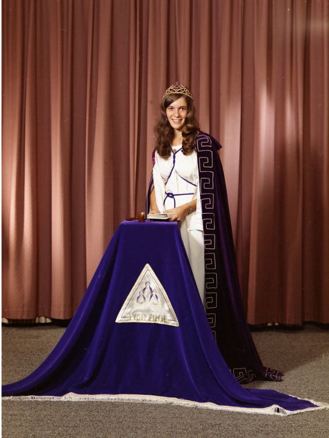 Linda Barber in ceremonial Masonic dress. She is wearing a tiara, a white dress, and a dark purple cape, September 28, 1973