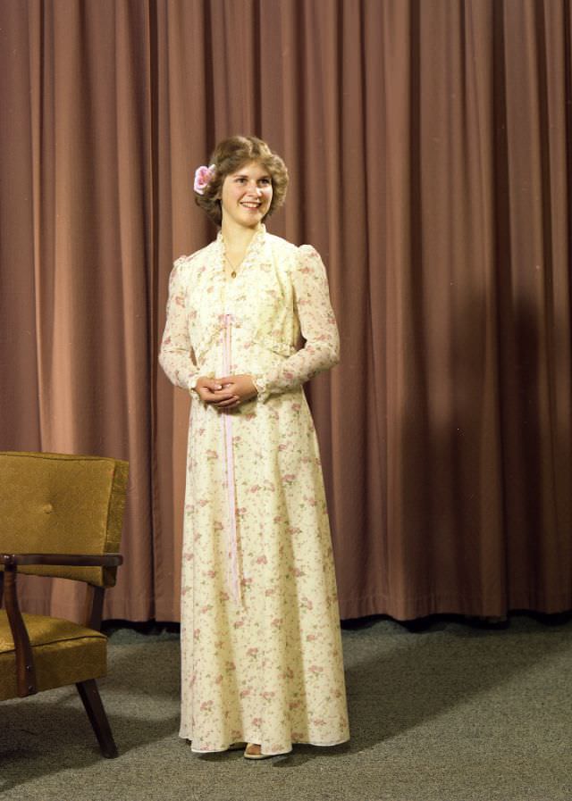 Portrait of a young woman wearing a long, cream-colored dress. She also has a pink flower in her hair, June 4, 1976