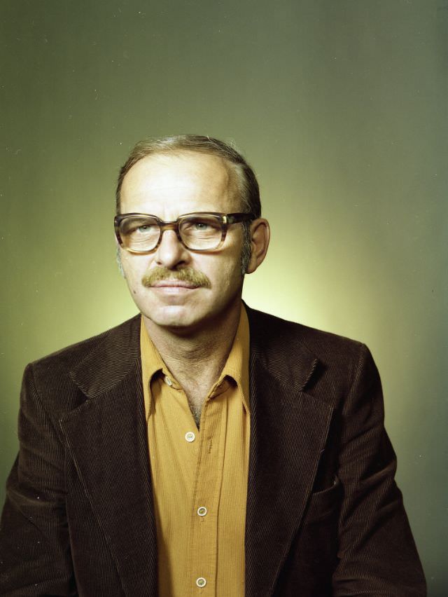 Portrait of a man. He has a mustache and glasses, wearing a mustard colored button-up shirt with a brown corduroy sports coat, September 9, 1978