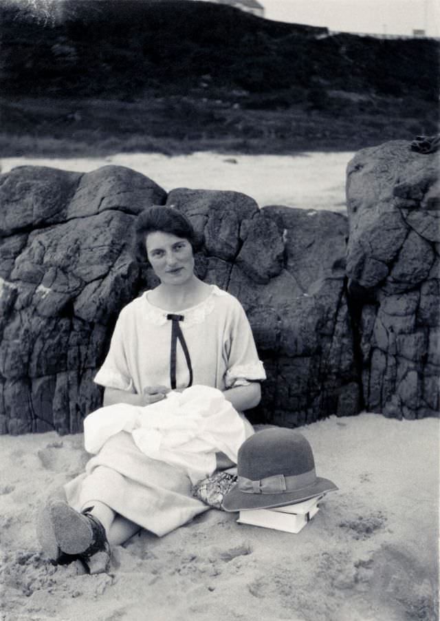 A young lady in a light-colored dress posing on a beach on an overcast day.