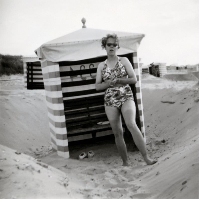 A bashful young lady in a two-piece swimsuit posing on a beach.