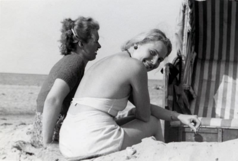 Two cheerful young ladies enjoying a day at the seaside. A typical German beach chair (Strandkorb) can be seen on the right-hand side of the picture, 1938