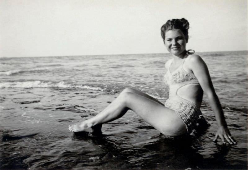 A young lady in a so-called Monokini swimsuit posing on the beach. The print is dated "1948" on reverse, 1948