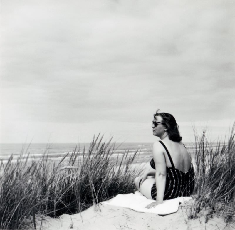 A brunette lady in a one-piece swimsuit posing at the seaside, 1955