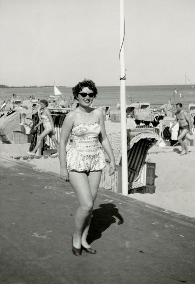 A young brunette lady in a fashionable one-piece swimsuit posing at the seaside, 1950s