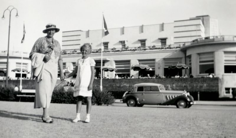 A fashionable lady and her daughter posing in front of a distinctive Art déco building in summertime.