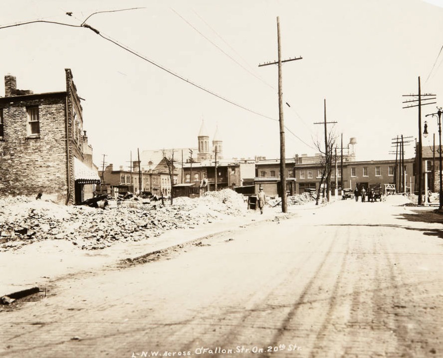 Piles of bricks on a lot near the intersection of O'Fallon and 20th streets in 1920, with the twin spires of St. Stanislaus Kostka church visible in the distance.