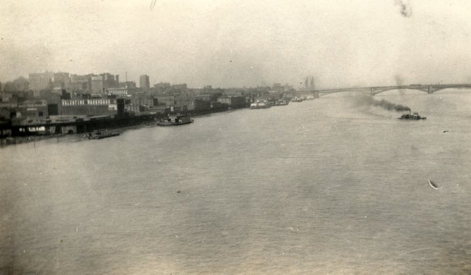 View of the St. Louis riverfront looking north from a bridge, with the Eads Bridge in the distance, Valentine Warehouse and elevated railroad in the foreground, 1927.