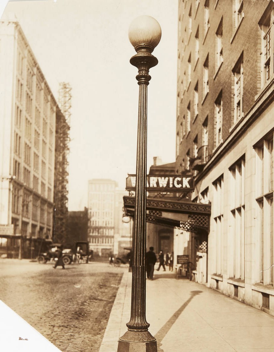 A streetlight on the sidewalk of 15th street just north of its intersection with Olive in 1920, with the entrance for the Warwick Hotel visible behind the streetlight.