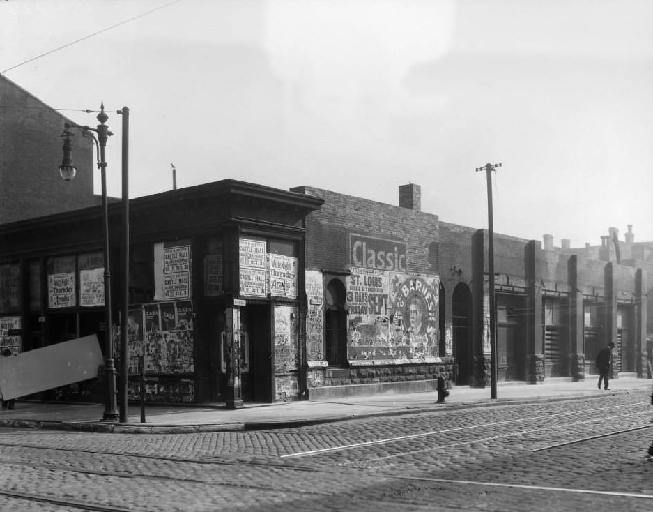 Southeast corner view of Olive Street and North 21st Street, with businesses such as George Doepke’s Grocery and posters for Al G. Barnes Circus visible, 1925