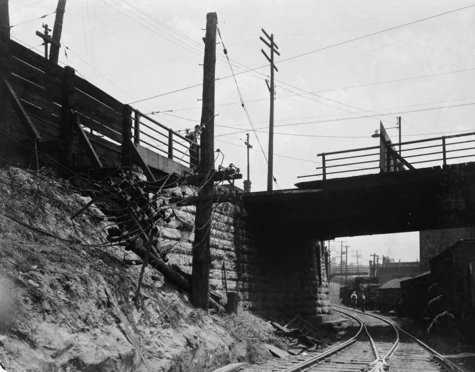 View of a damaged utility pole at train tracks, 1925
