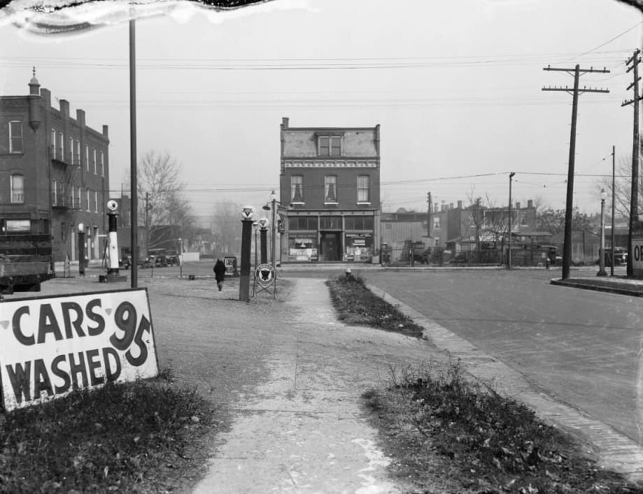 North view at the intersection of Natural Bridge Ave. and Clarence Ave., with Conoco Gas Station, D. R. Calkins Used Cars, and a car wash sign visible, 1925