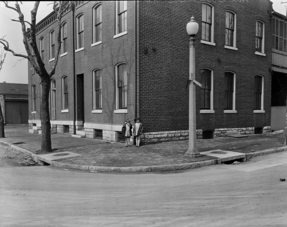 Two little girls standing on the northwest corner of Blair Avenue and Benton Street, with nearby brick residences visible, 1925