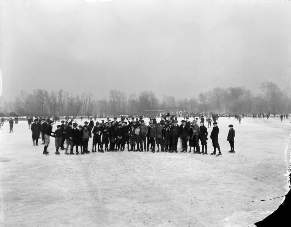 Group of men and boys on skates posing on a frozen pond, 1927