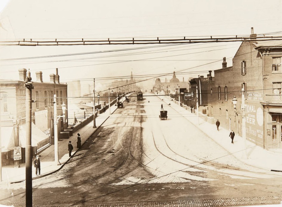 12th Street viaduct looking north from Chouteau Avenue, with storefronts for the John Thomann liquor store and the John H. Heller drug store visible, 1920