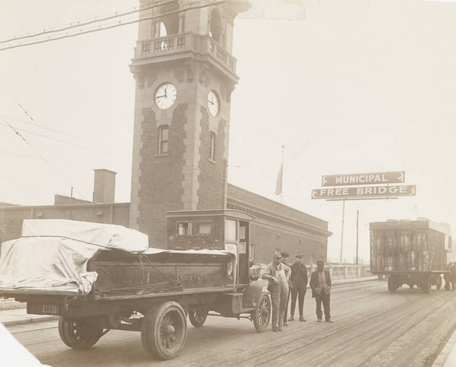 Entrance to the Municipal Free Bridge, with four men standing next to a truck of the Swift & Company parked at the entrance, 1920