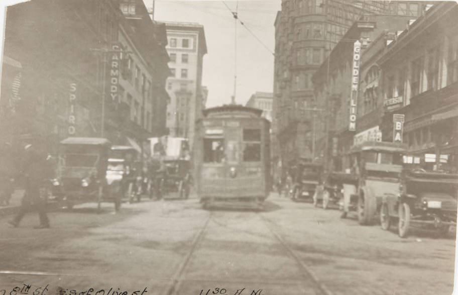 Streetcar moving past automobile traffic on 8th Street, with signs for various theaters and establishments visible, 1920