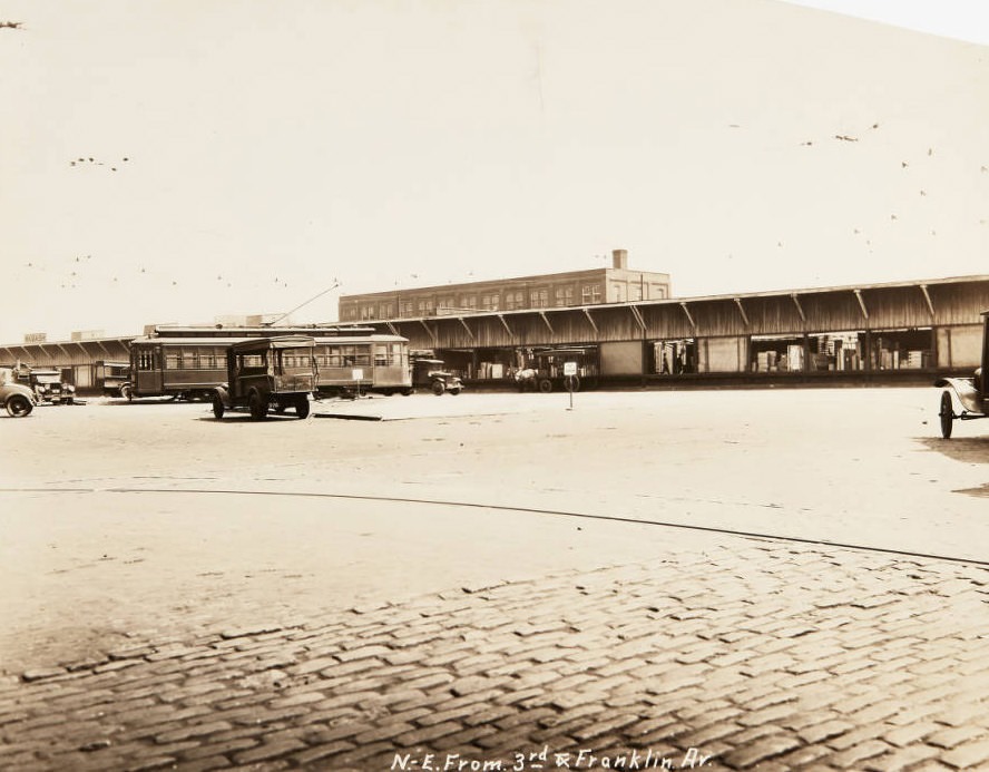Trucks and a streetcar loading at delivery docks located at Third Street and Franklin, 1920
