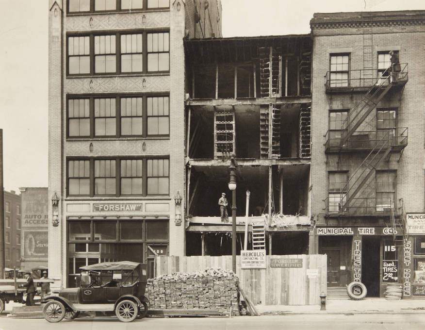 Row of buildings on the 100 block of N. 12th Street with Forshaw Stove Repairs having its exterior wall replaced and Municipal Tire Co. storefront, 1920