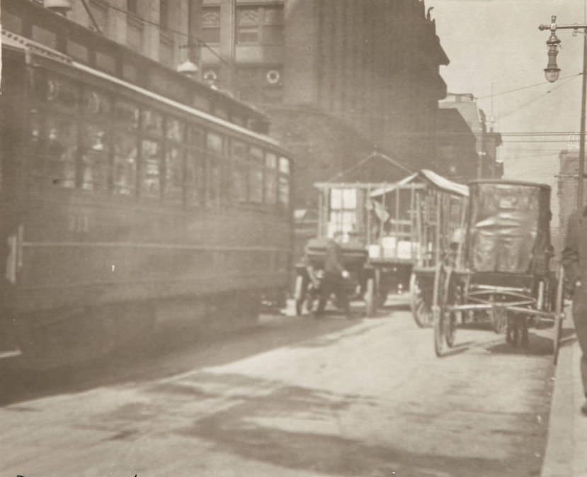 Traffic scene at the intersection of Olive and Seventh Streets with streetcars, horse-drawn carts, and pedestrians sharing the road, 1920