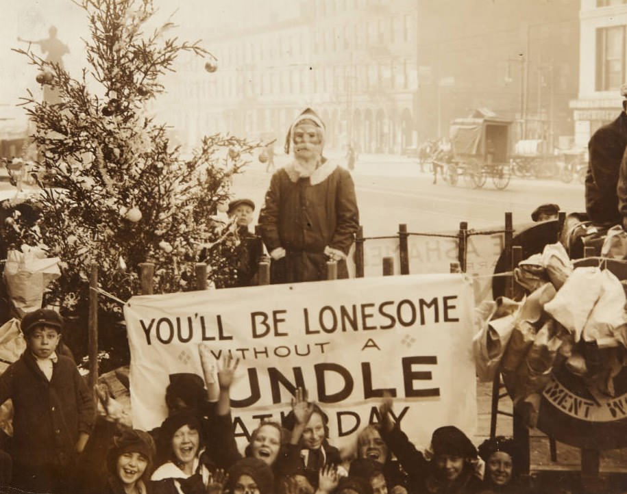 Group of children gathered around a Christmas tree and a man dressed as Santa Claus on downtown street, 1920